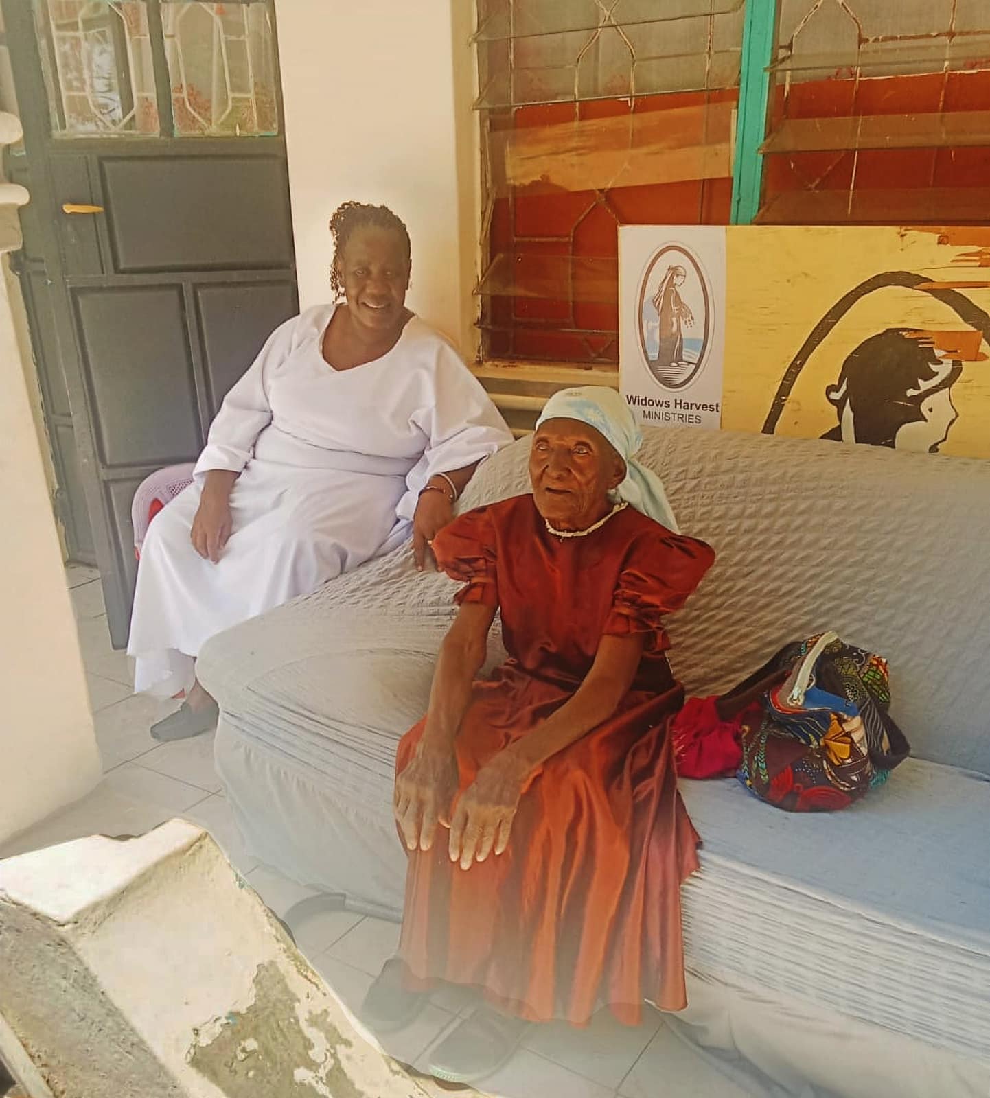 Abigael Atieno (left) sitting with a widow in Kenya
